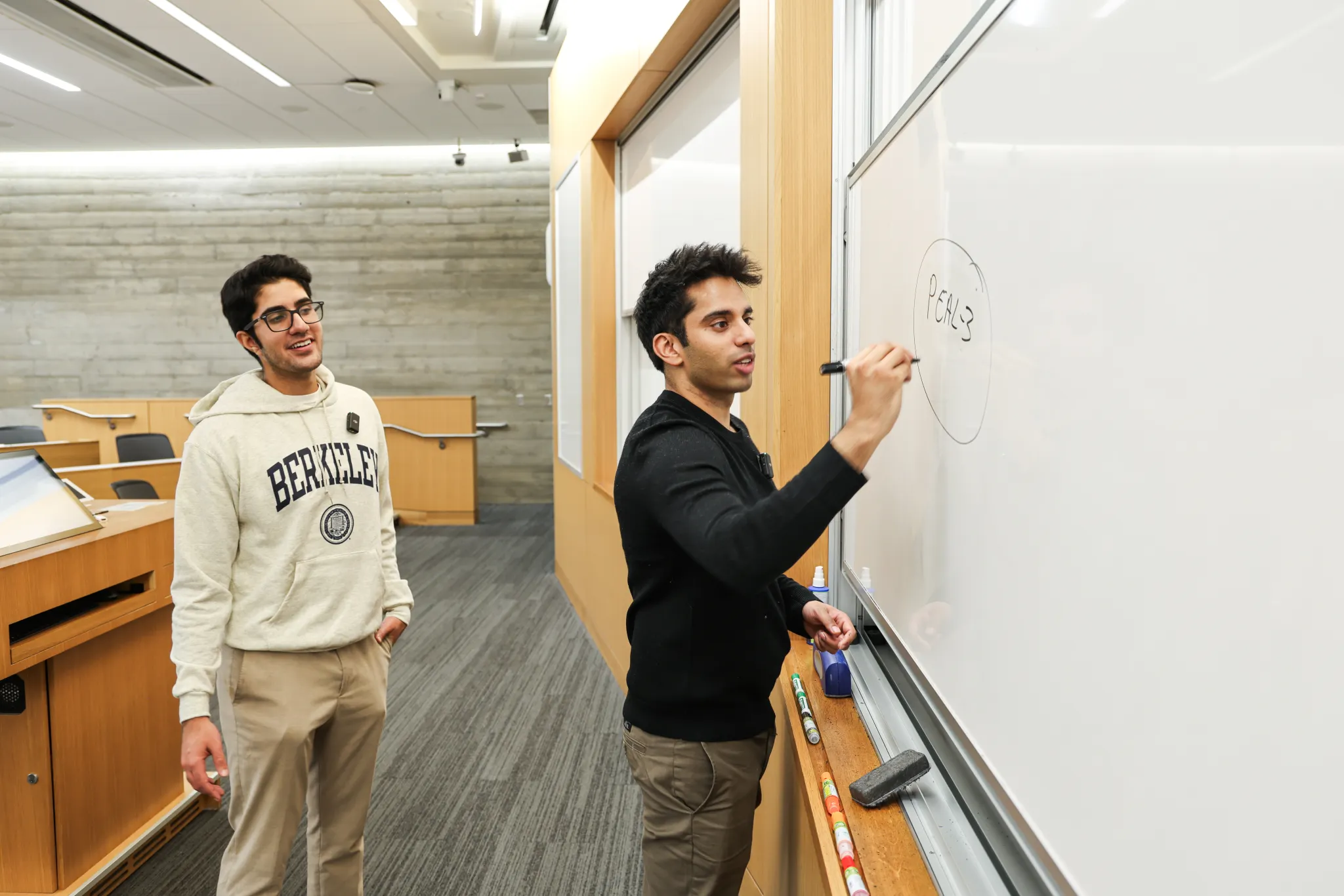 Hassan Akram writing the Peal-3 framework on a whiteboard for a student at UC Berkeley.