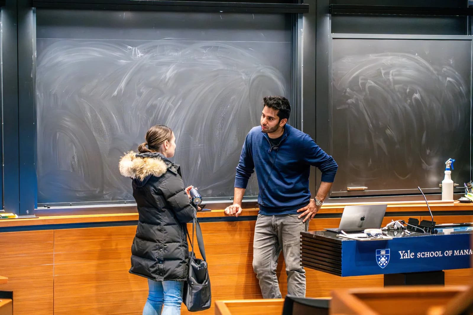 Hassan Akram in conversation with a candidate at the front of a Yale School of Management lecture theatre after an invited session.