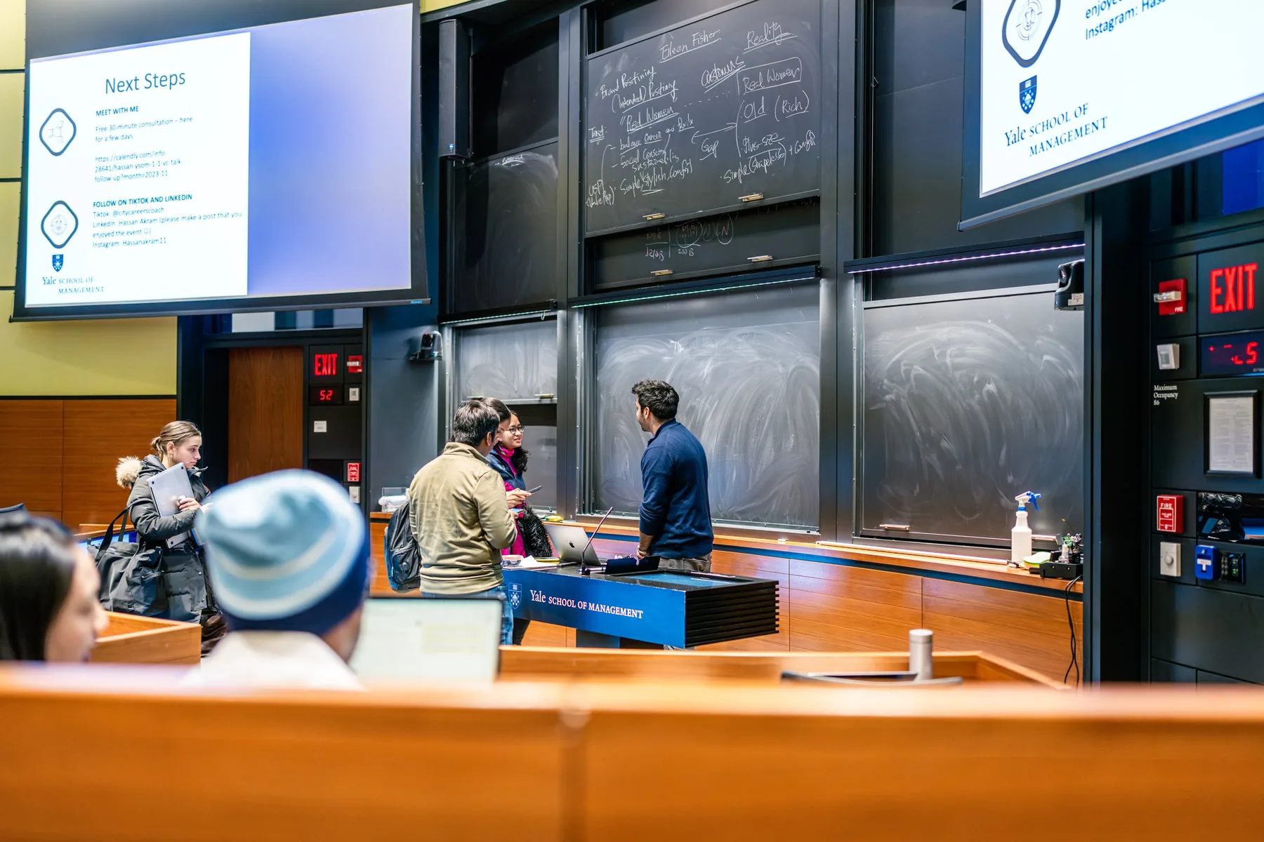 Students waiting to speak with Hassan Akram at the front of a Yale School of Management lecture theatre after a session.